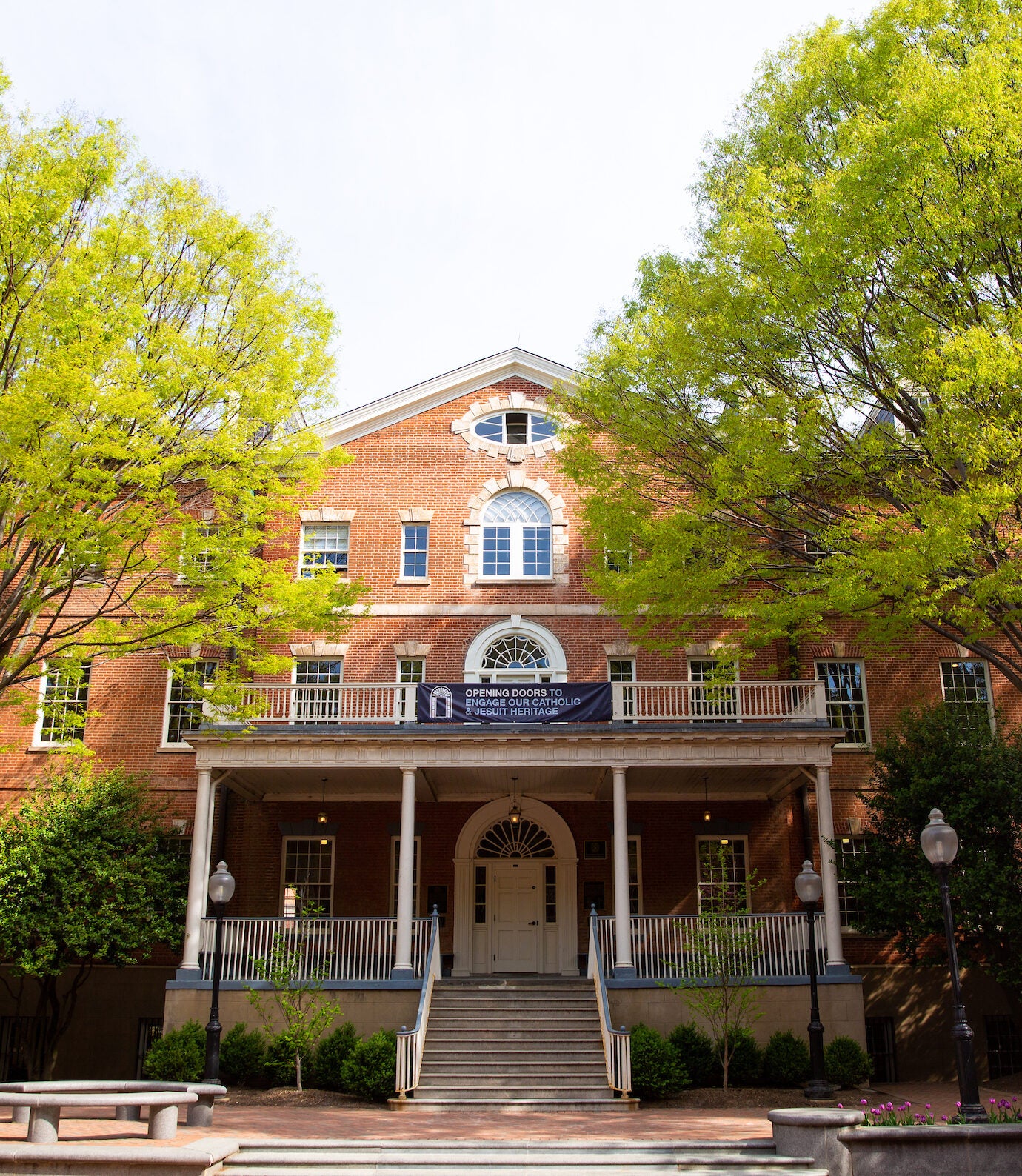 Front view of a red-brick building (Old North) at Georgetown University, framed by tall green trees. 
