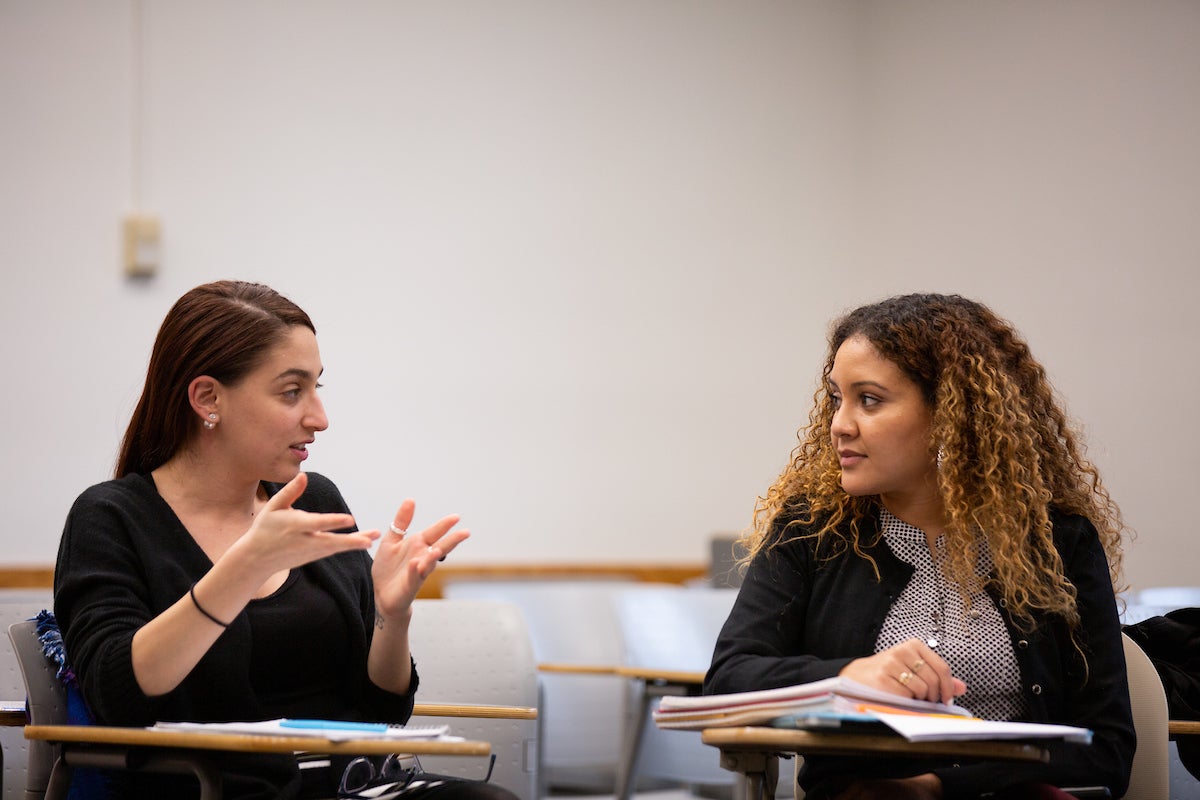 Two people engaged in conversation at desks.