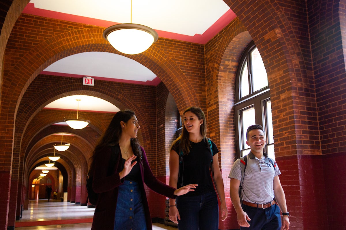 Three students walking inside Healy Hall.