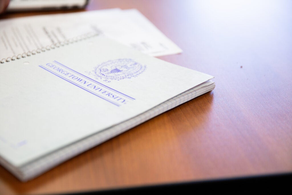 Georgetown notebook and stack of papers on desk.
